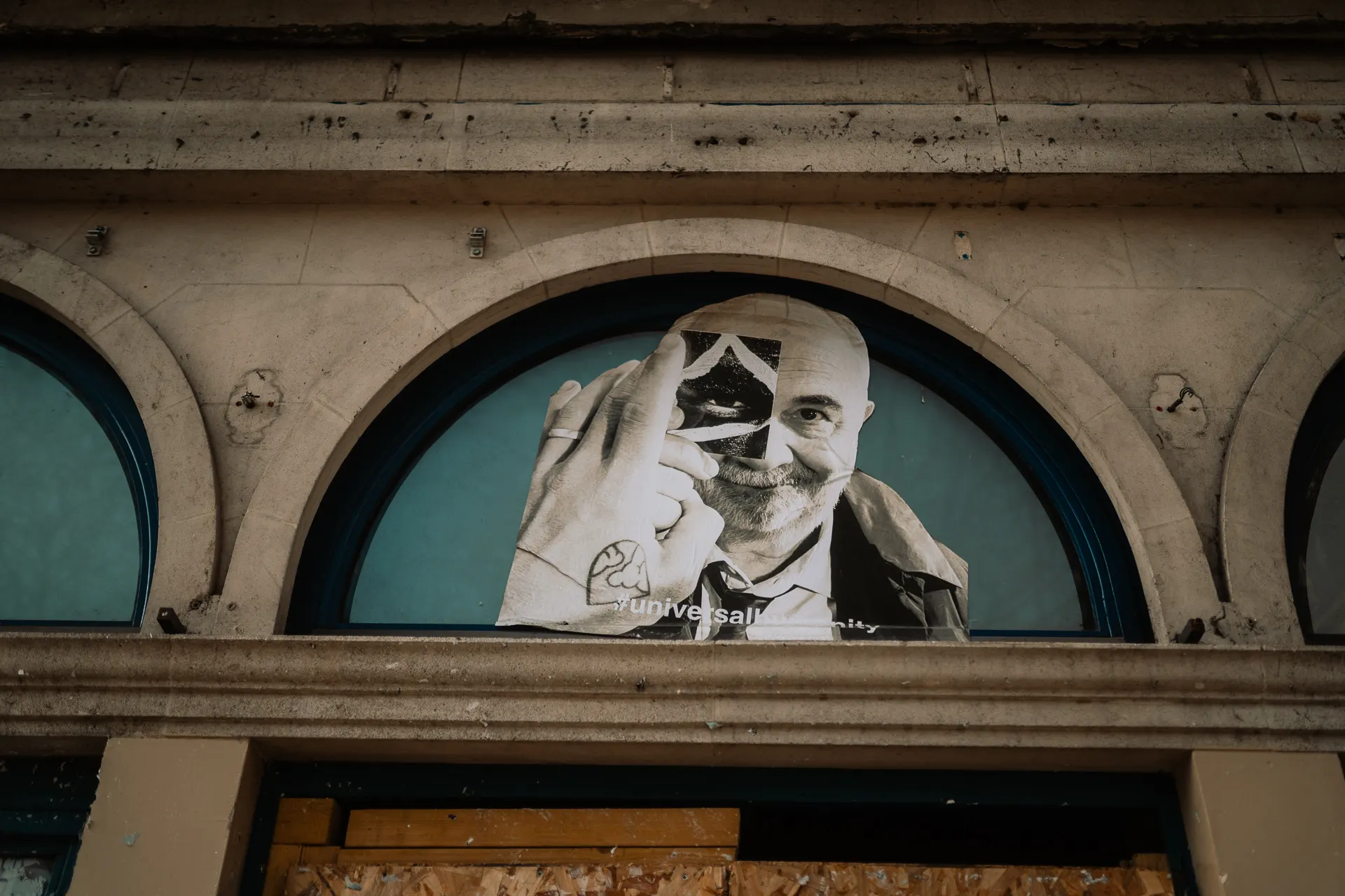 Paris archway with a portrait poster and a passing stranger